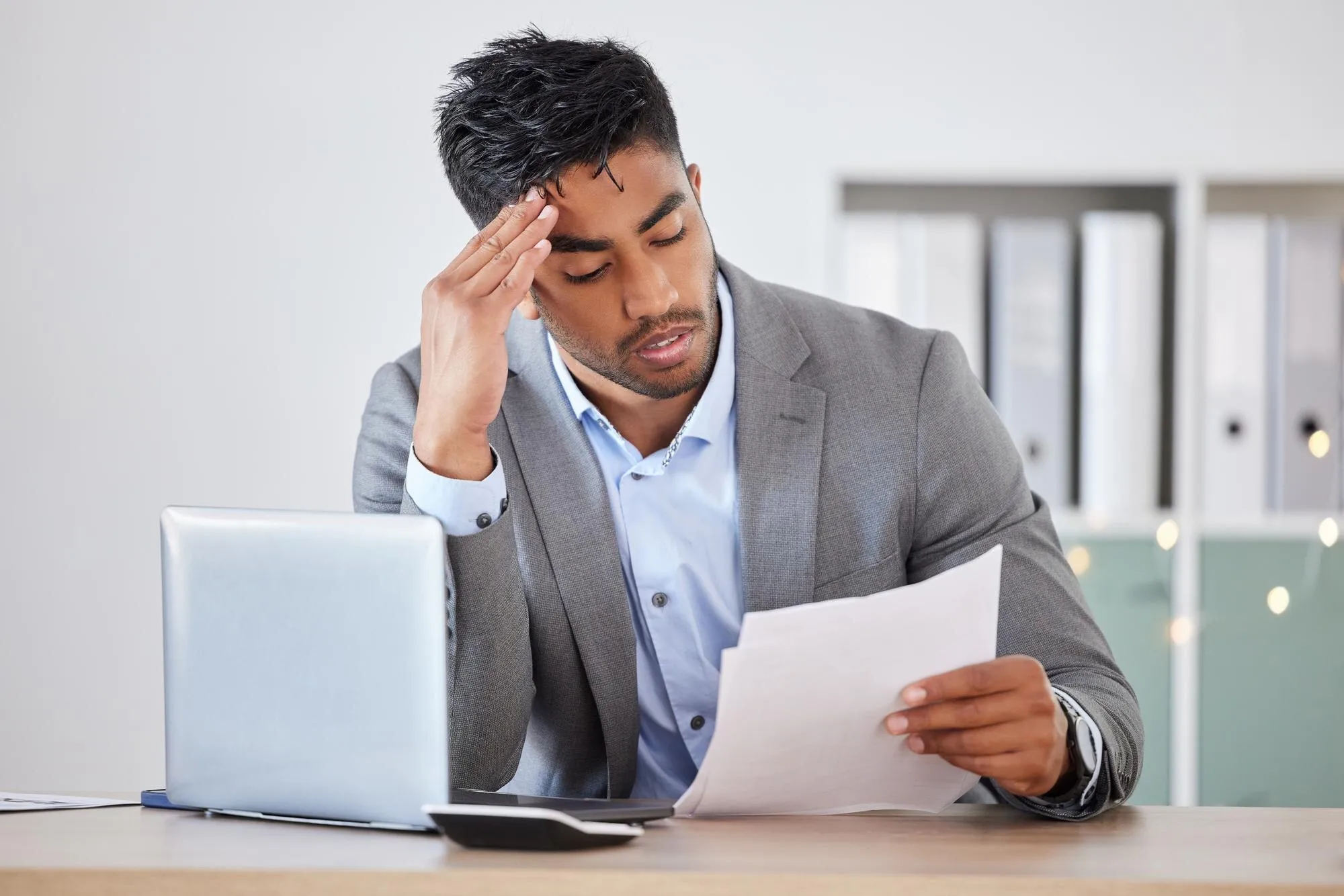 Laptop de empresário e estresse com papel orçamentário e dor de cabeça para ansiedade dor de cabeça e esgotamento no escritório Trabalhador corporativo e dívida