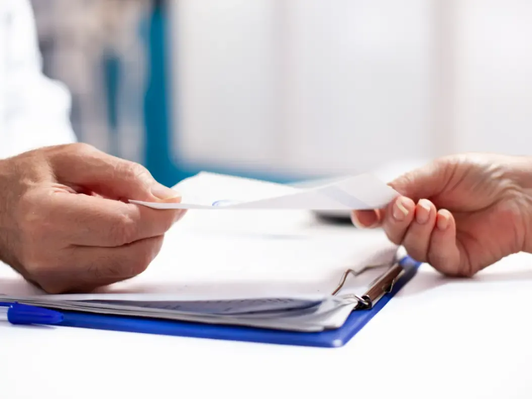 Paciente recebendo um documento médico das mãos do profissional de saúde