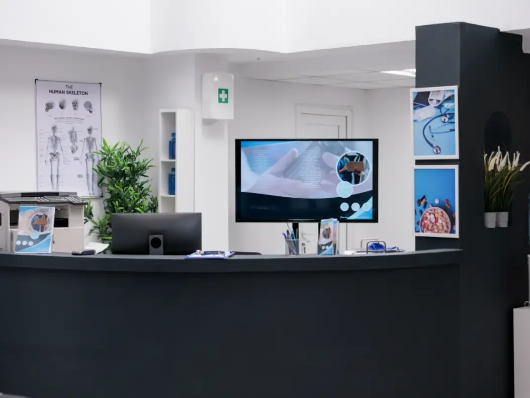 Balcão de atendimento de hospital com computador e formulários de cadastro sobre o tampo