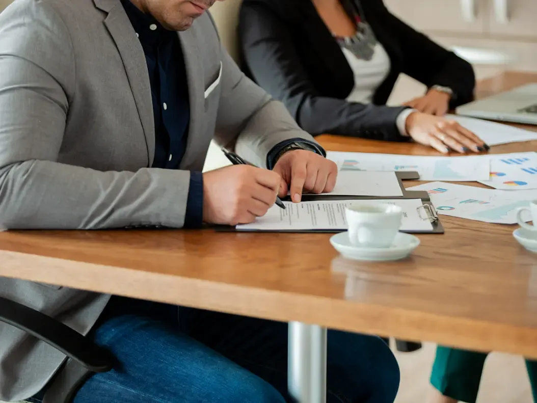 Close da mão de um homem assinando um contrato na sala de reunião